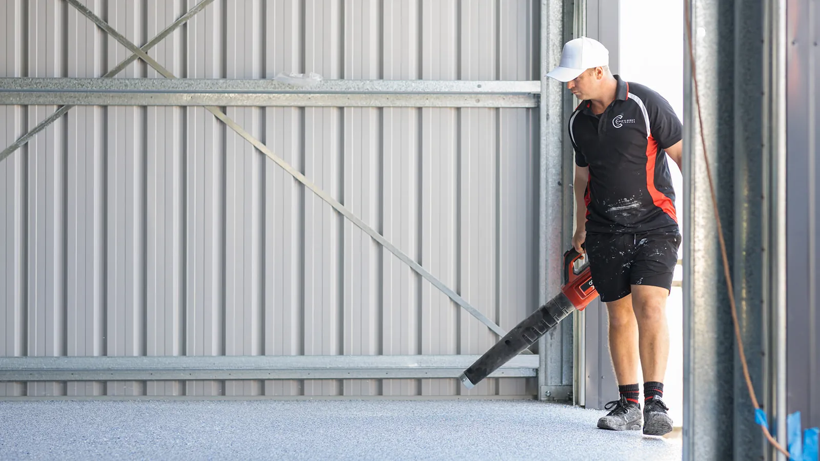 Installer using a blower to clear loose flakes near the shed door