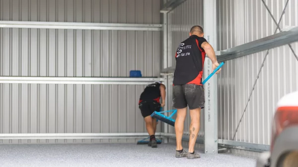 Two installers spreading decorative flakes across a new epoxy shed floor