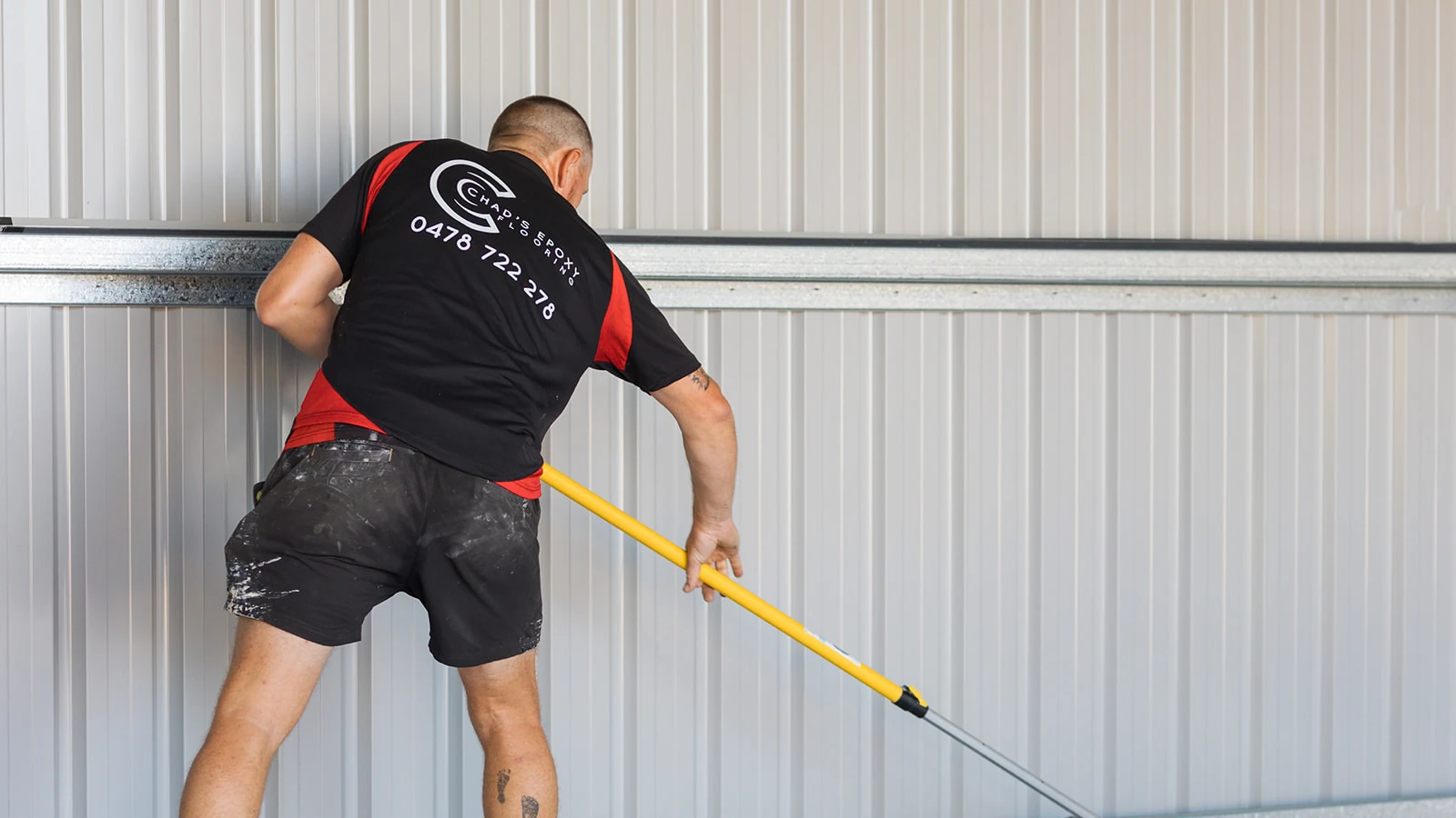 Installer sweeping flakes from the edges of a new epoxy shed floor