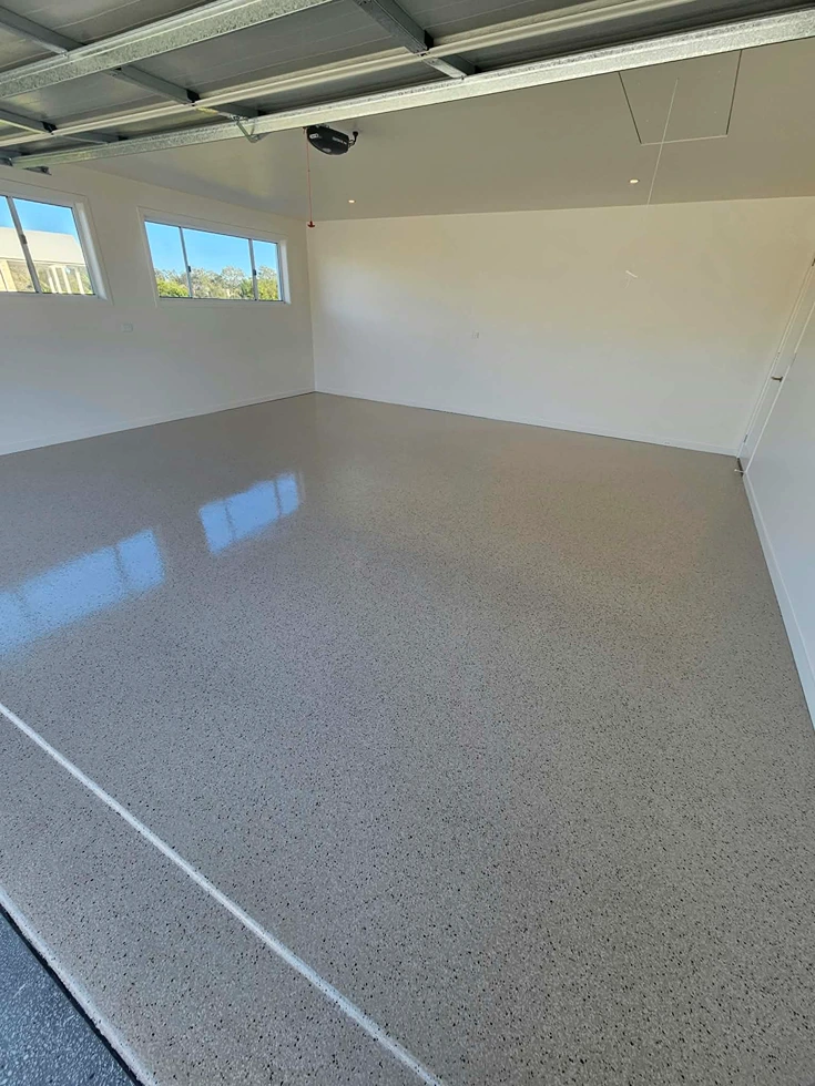 Glossy grey flake epoxy garage floor with contrasting dark grey borders by Chad's Epoxy Flooring.