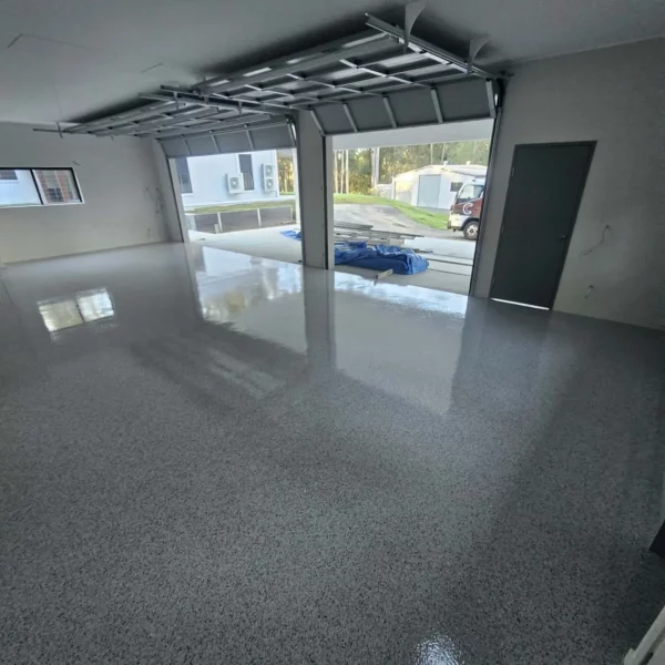 Glossy grey flake epoxy garage floor with the roller door open, installed by Chad's Epoxy Flooring