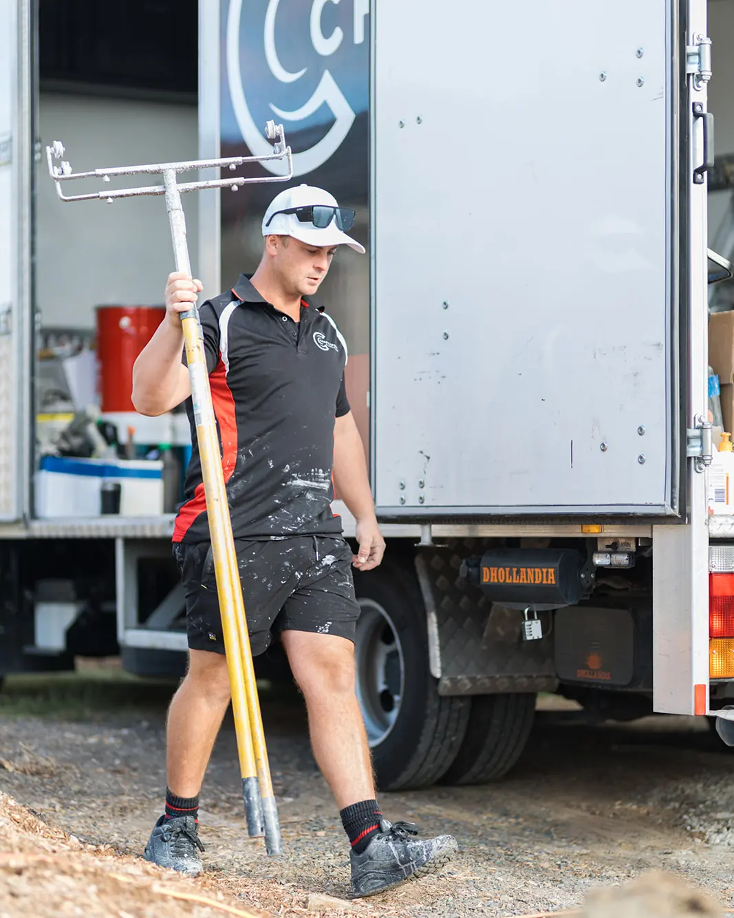 Chad's Epoxy Flooring installer carrying a flake spreading tool beside the work truck in Marburg