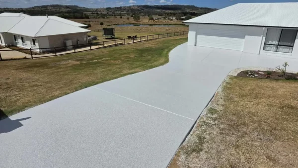 Long light grey coated driveway leading to a shed