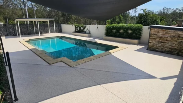 Finished grey pool surround floor beneath a shade sail