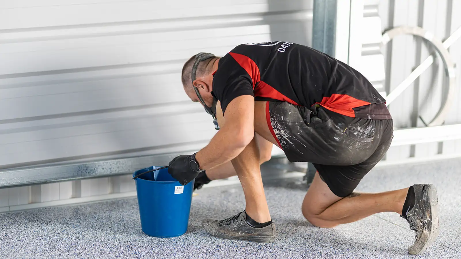 Epoxy technician cutting in clear topcoat along the base of a shed wall