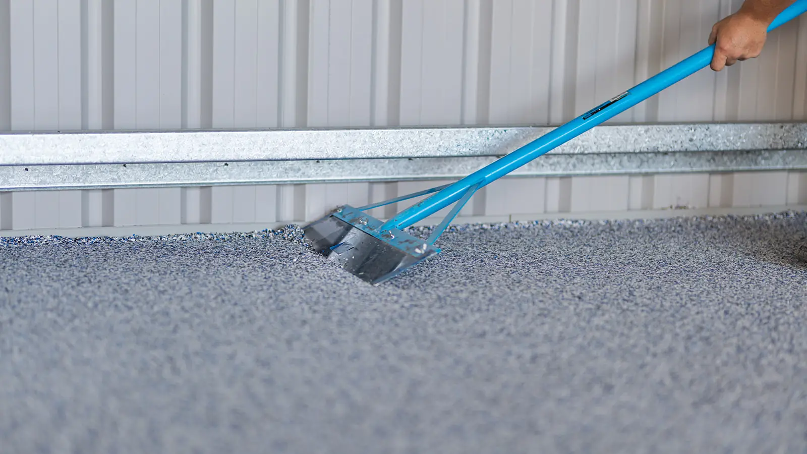 Close-up of loose epoxy flakes being scraped from a cured flake floor