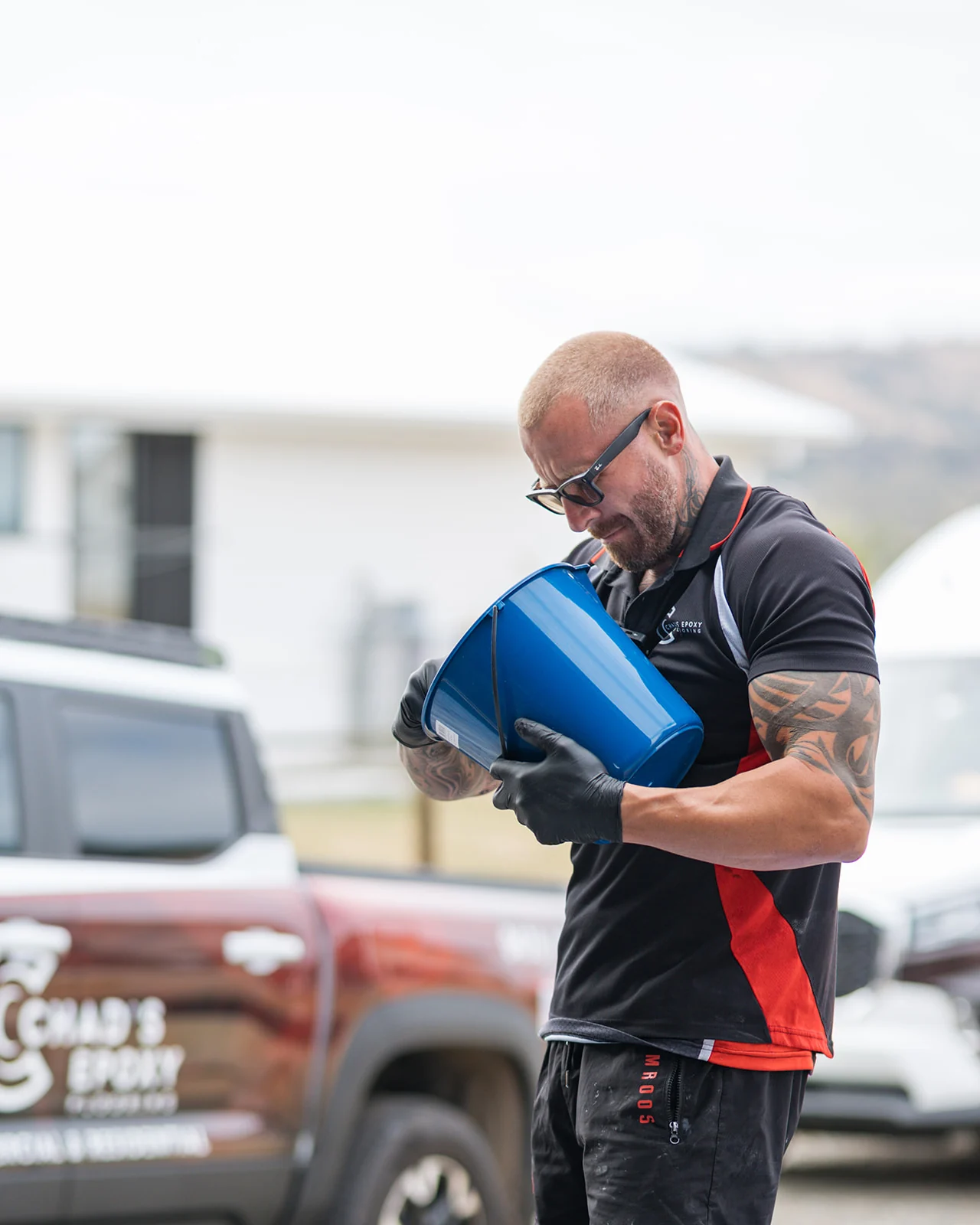 Chad's Epoxy installer pouring clear coat into a bucket beside the branded ute