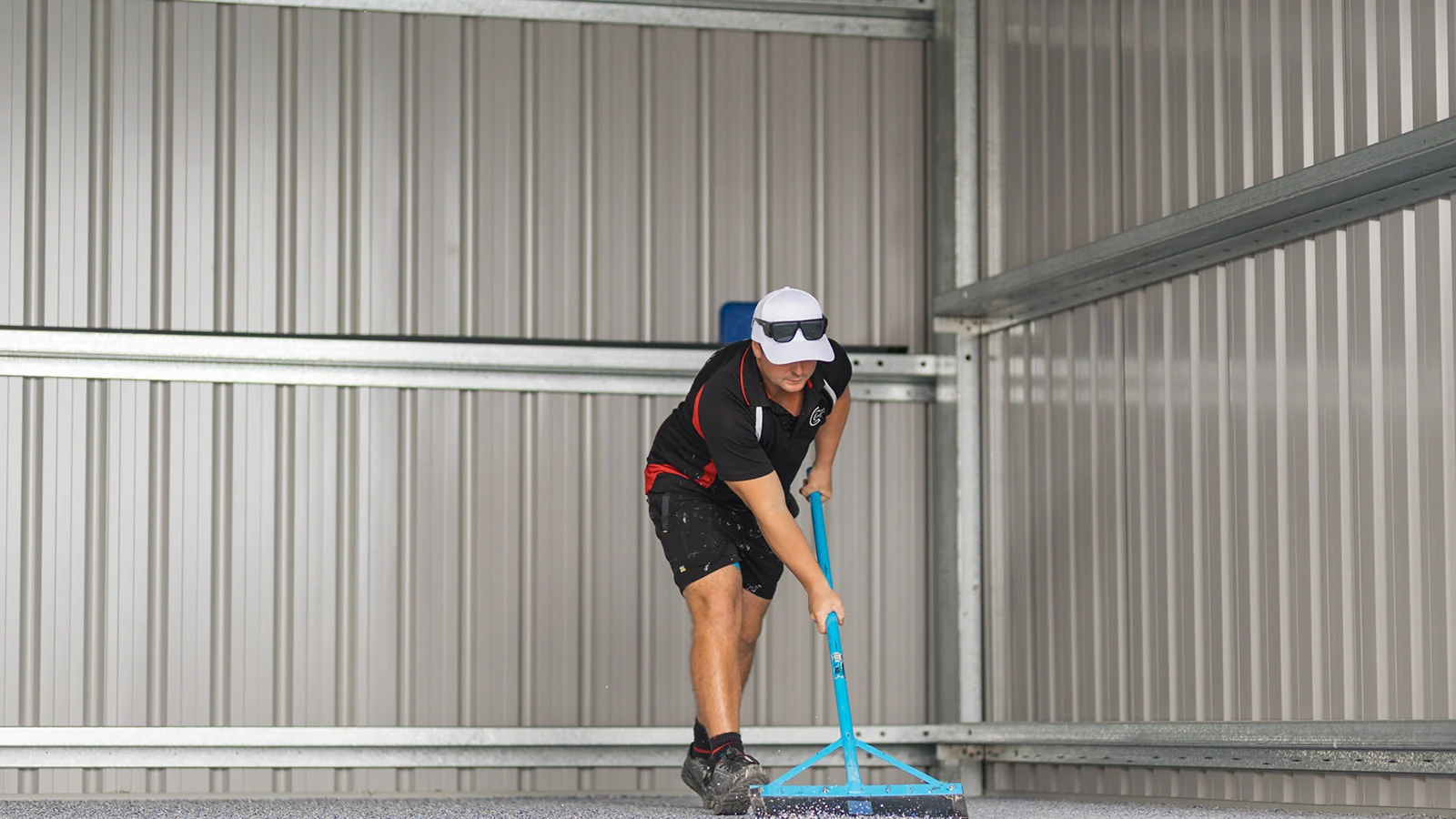 Installer scraping loose flakes on a flake epoxy floor inside a steel shed