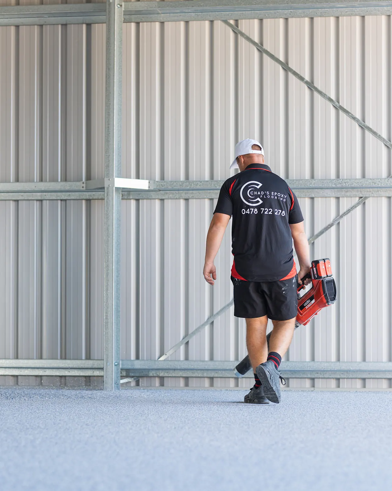 Chad's Epoxy installer walking across a flake floor with a cordless blower