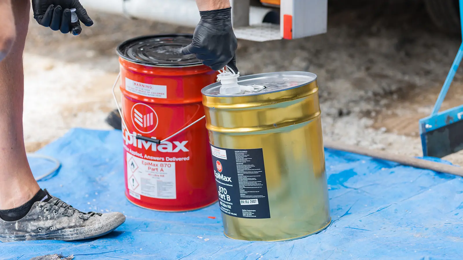 Installer opening EpiMax epoxy tins on a tarp for on-site mixing