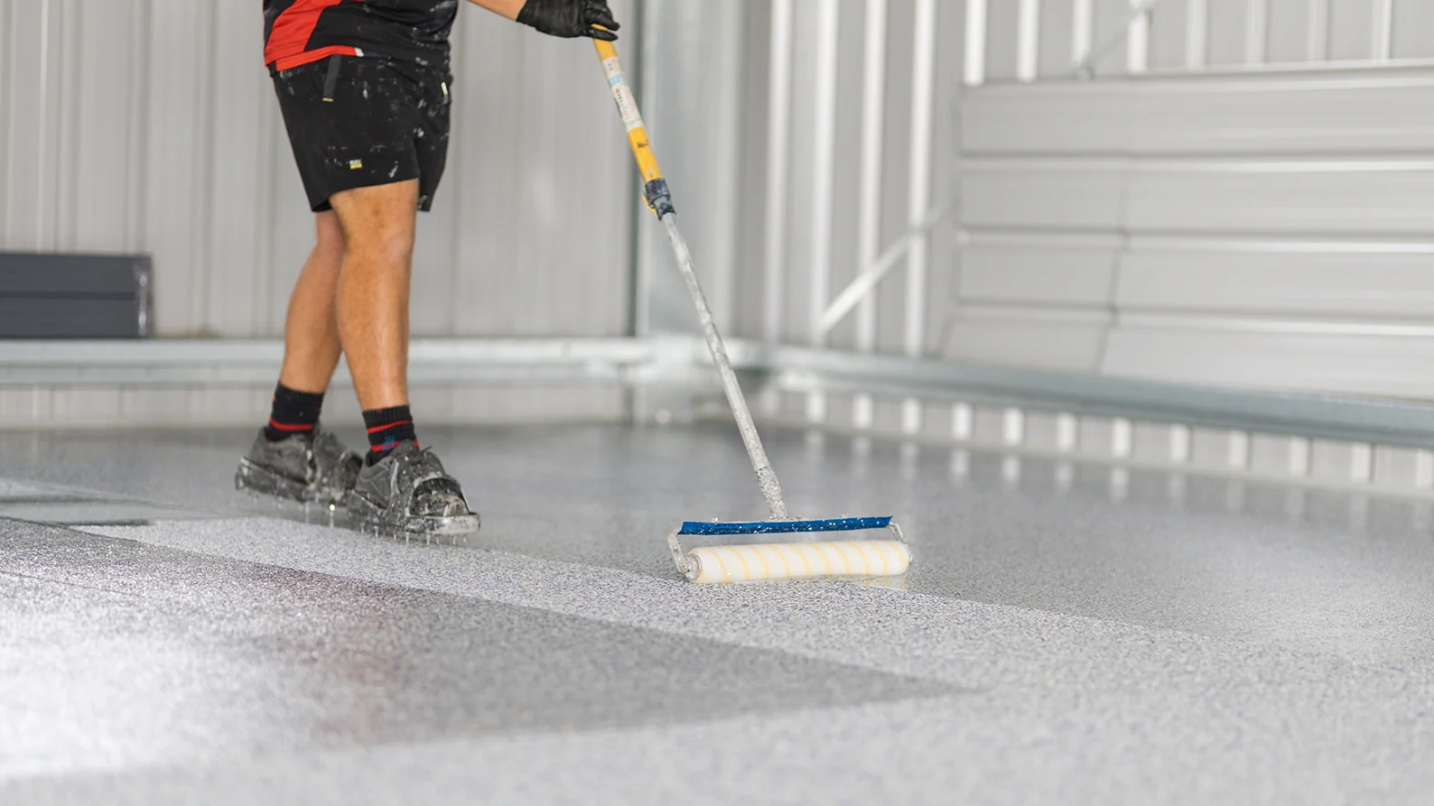 Installer rolling glossy clear coat over a grey flake epoxy floor