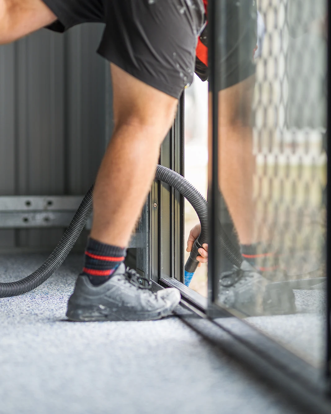 Tradesman vacuuming a garage floor to prepare it for epoxy coating